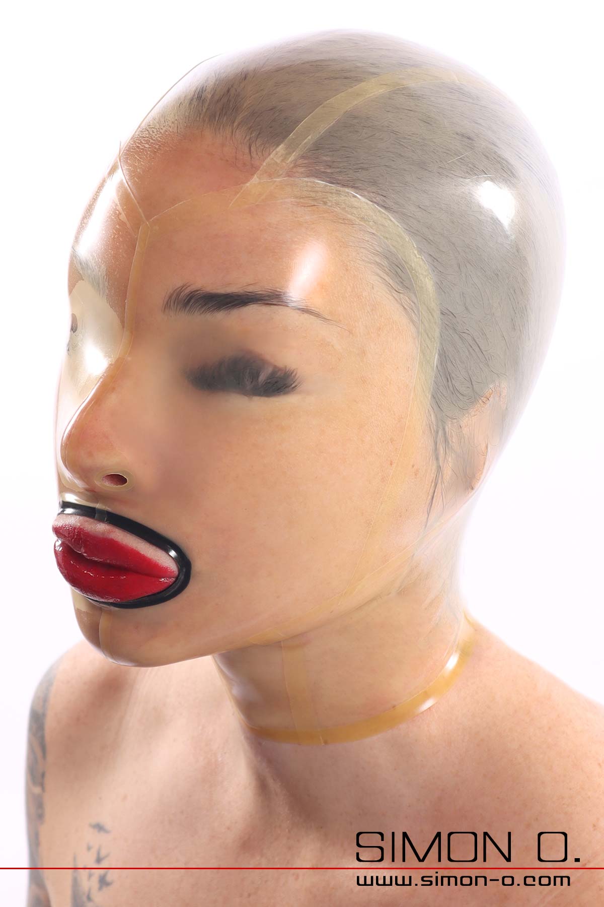 A transparent, shiny latex mask without eye openings fits snugly around the face of a woman with red lips.