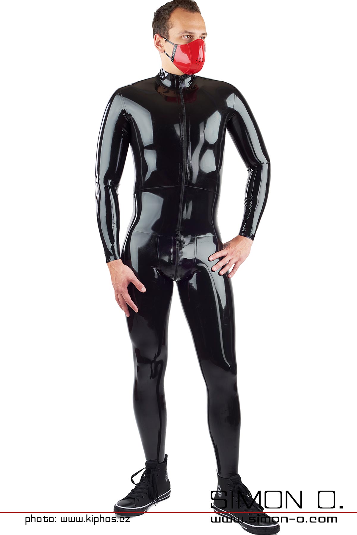 Ein Mann trägt einen schwrzen engen Latex Catsuit mit einem eingearbeiteten Miedergürtel