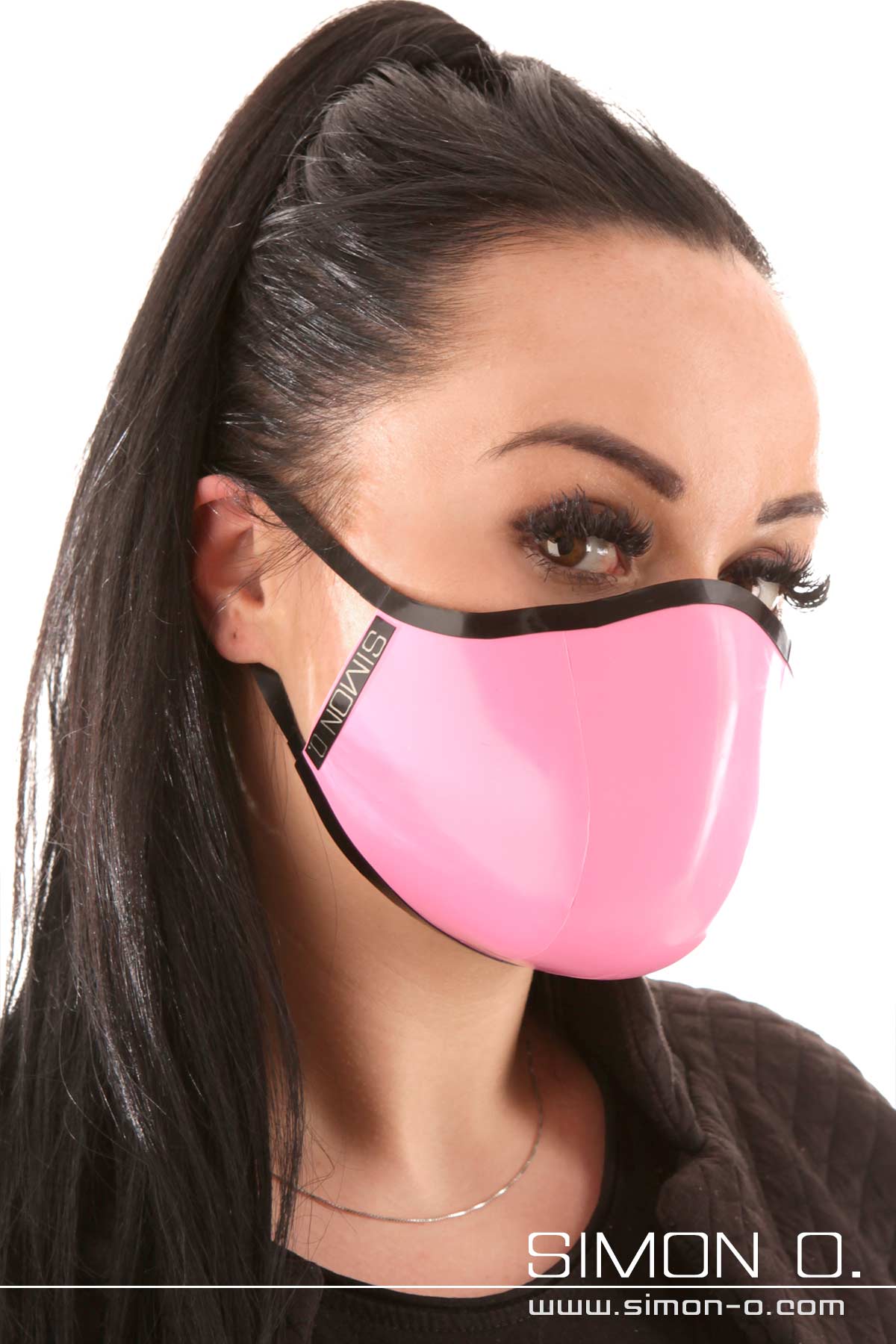 A dark-haired woman is wearing a shiny covid 19 latex face mask in pink