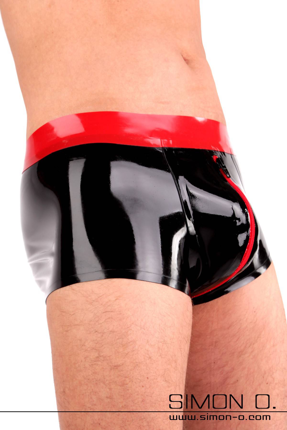 A man wears a black shiny latex shorts with condom and codpiece