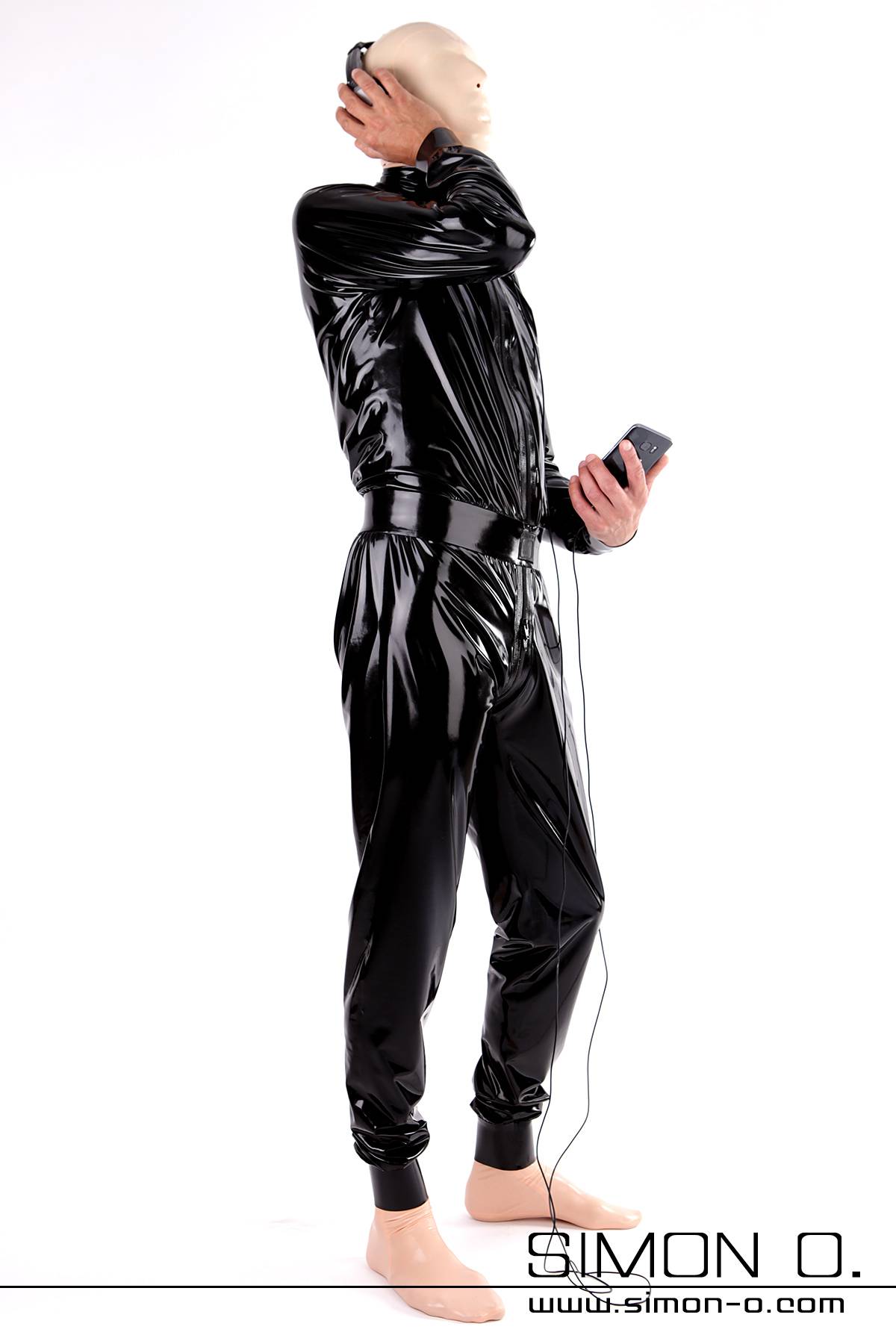 A man wearing a looser comfortably cut shiny homewear suit in black latex 