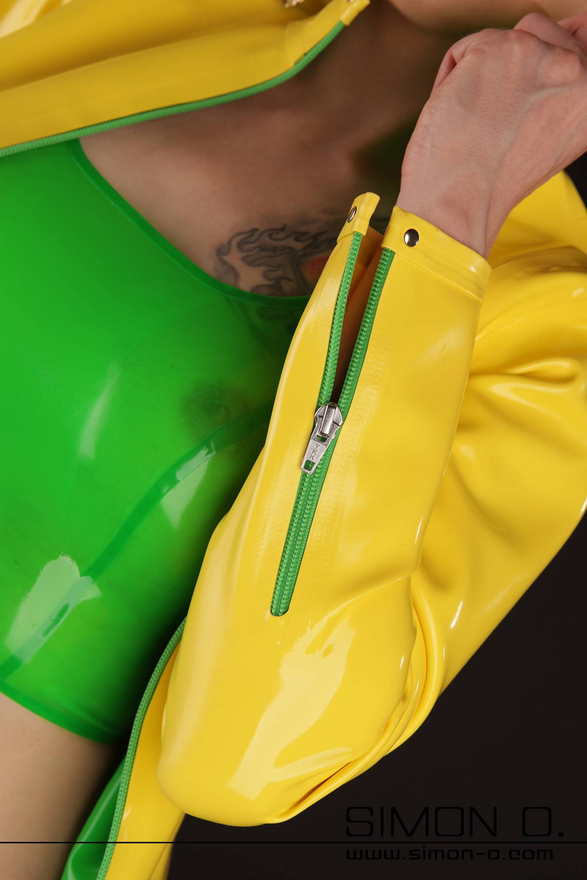 A woman in a yellow latex jacket with pockets and green zipper