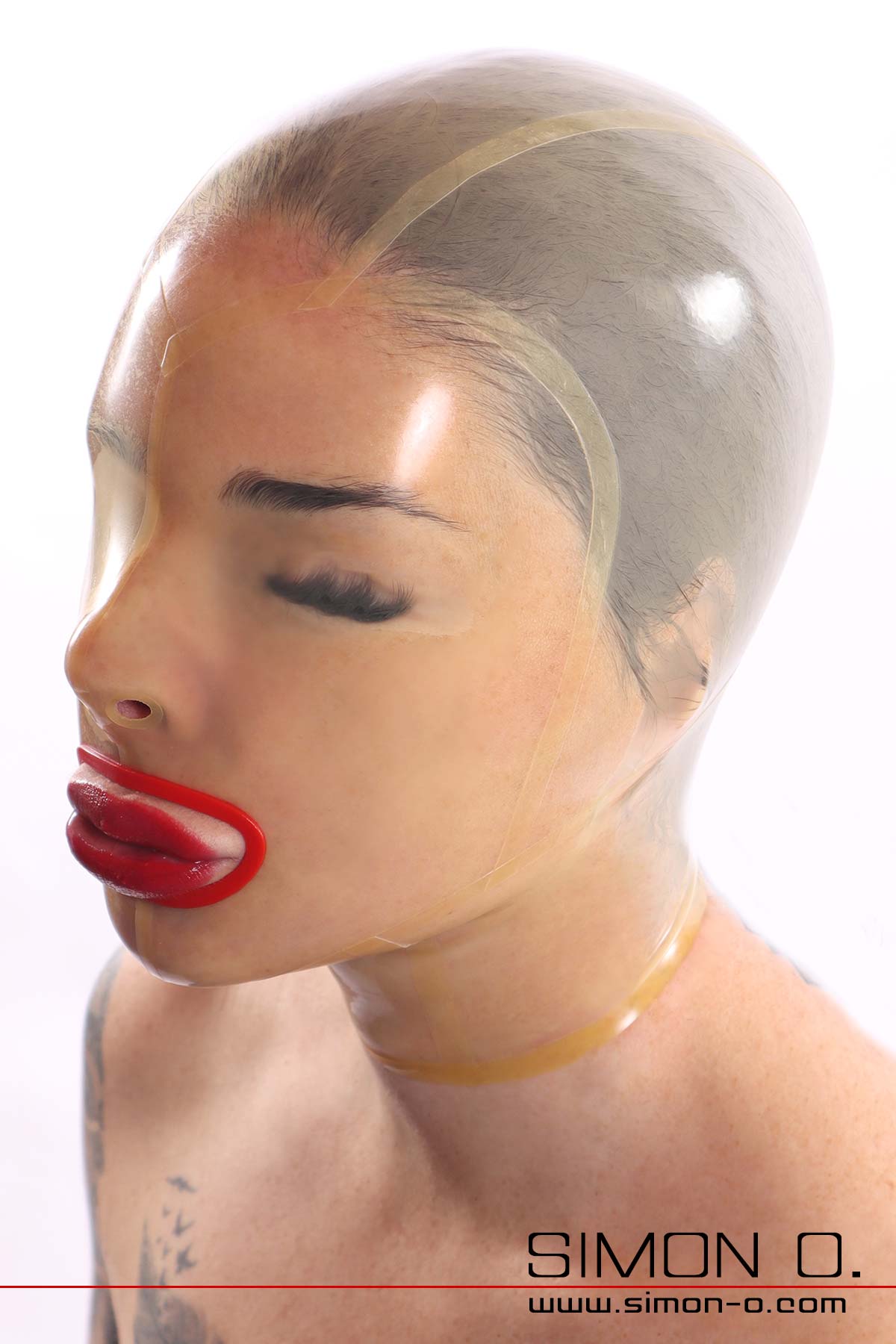 A shiny transparent latex mask without eye openings with a red-lined mouth fits snugly around a woman's face.