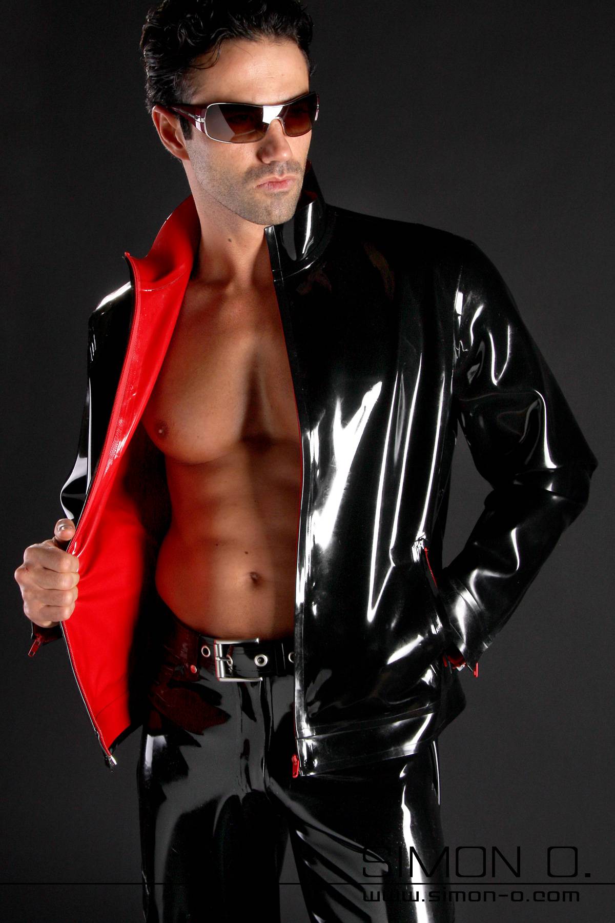 A man wears a black shiny latex jacket with red latex lining