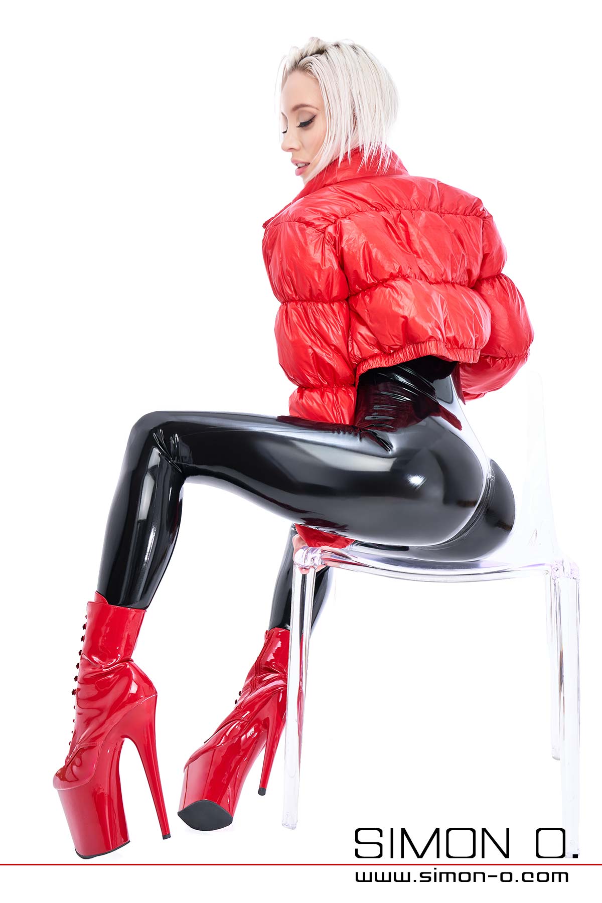 A sexy lady wears a shiny black latex catsuit with a red down jacket and high heels.