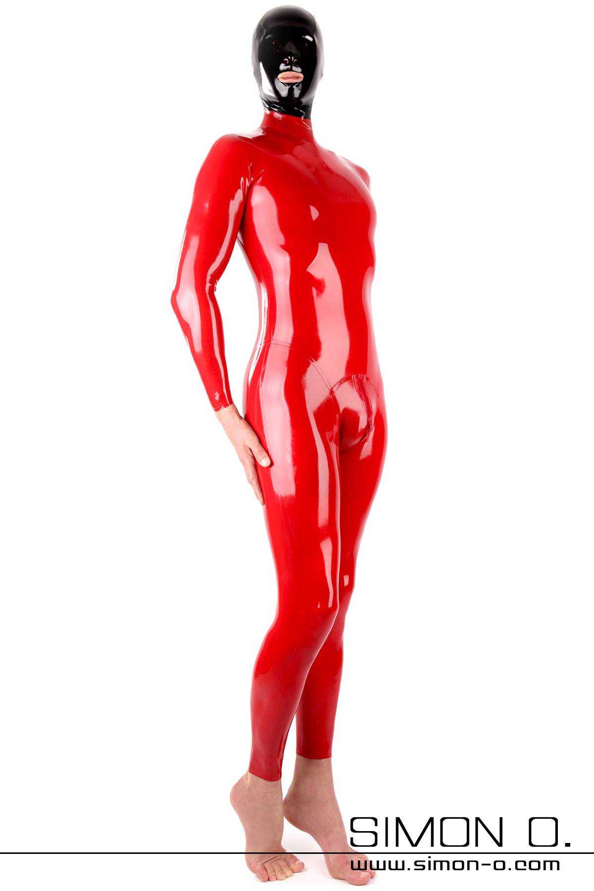 A man wears a tight shiny red latex suit with crotch zipper and a black latex hood seen from the front