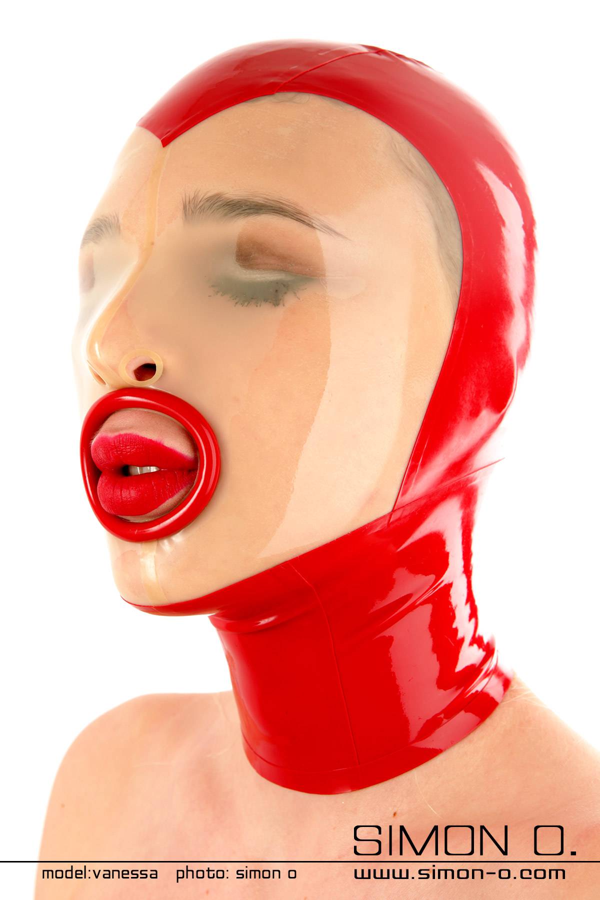 Latex hood in red with transparent insert in the face area. Eyes closed and at the mouth there is a red ring.