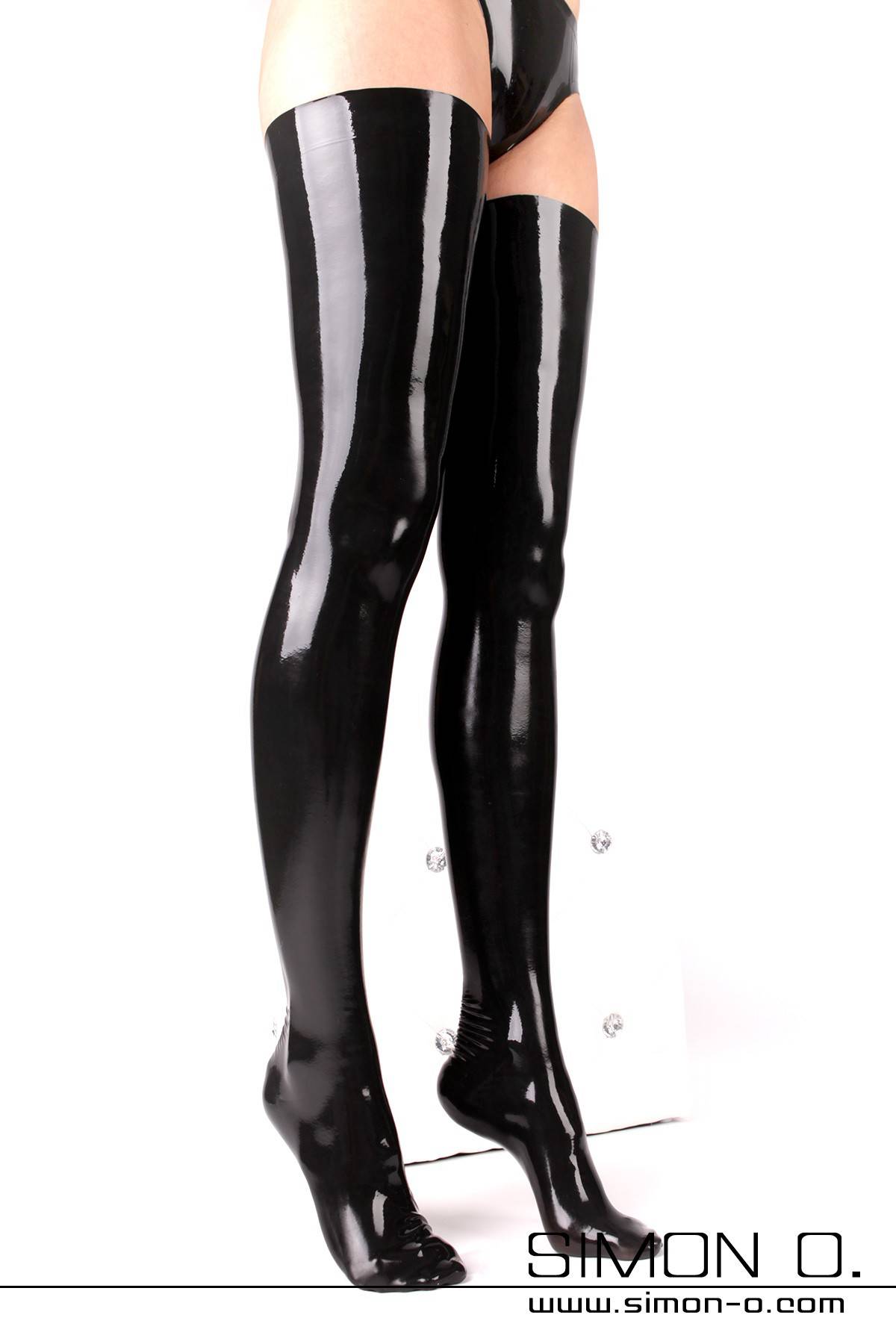 Women's legs in shiny black latex stockings with a snug fit