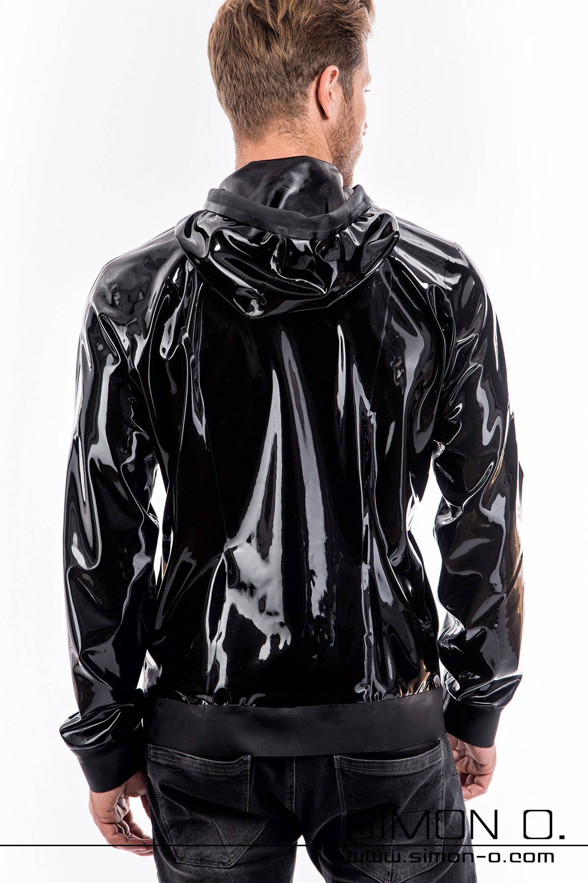 A blond man wears a latex jacket with hood and in black, seen from behind.