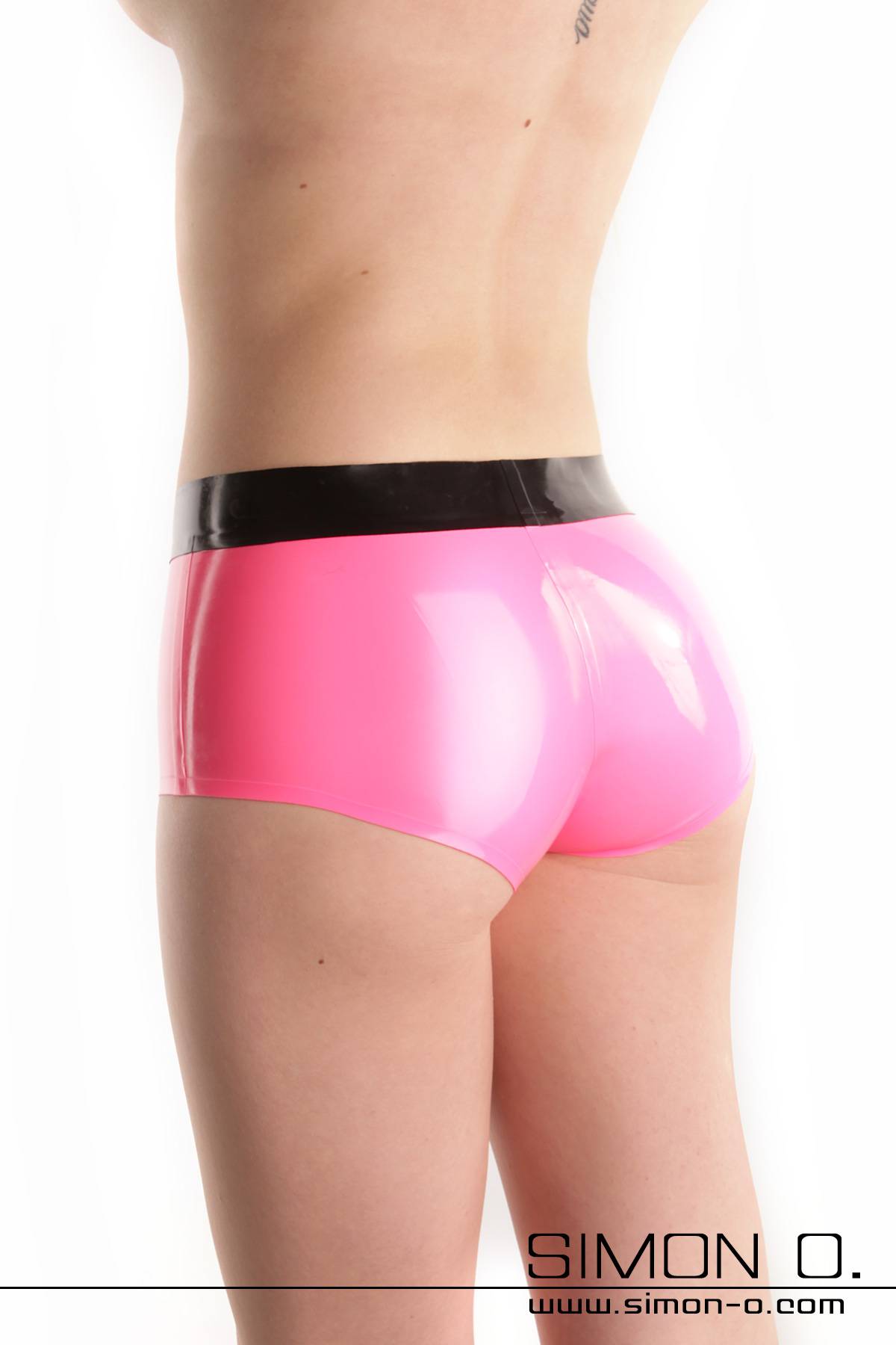 A shiny tight latex hot pant in pink with black waistband seen from behind