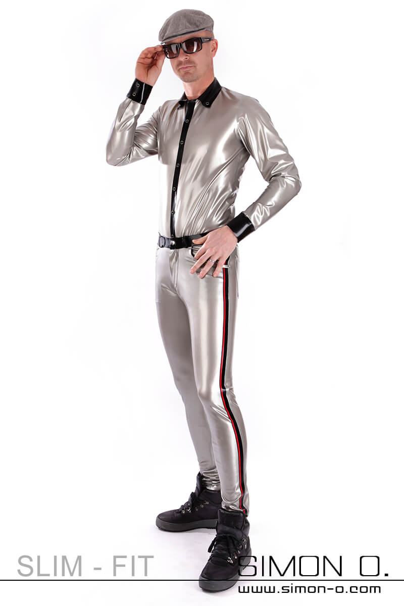 A man wears tight latex trousers with contrasting colored stripes on the sides. A matching latex shirt in silver.