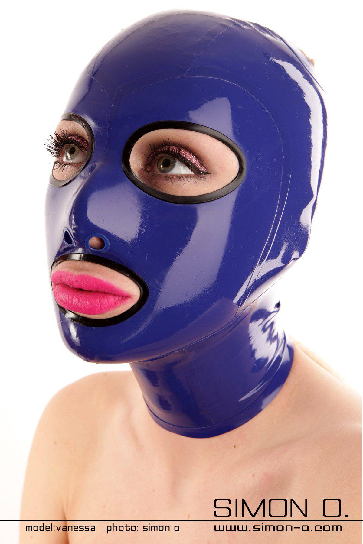 Eine  Frau mit einer glänzende blauen Latexmaske, die Kopf und Hals umhüllt und präzise Aussparungen für Augen und Mund aufweist, wodurch ein rätselhafter Reiz entsteht, der einem Sklavin würdig ist.