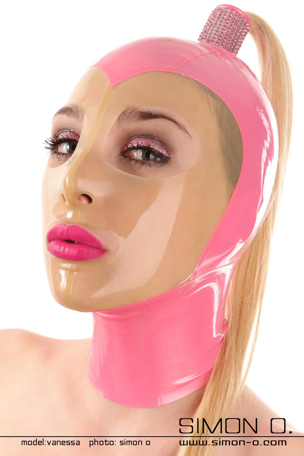 A person is wearing a pink latex mask with a transparent face and an attached blonde hairpiece.