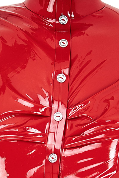 Close-up of a bright red, glossy latex blouse with a series of white buttons embossed with  "SIMON O." 