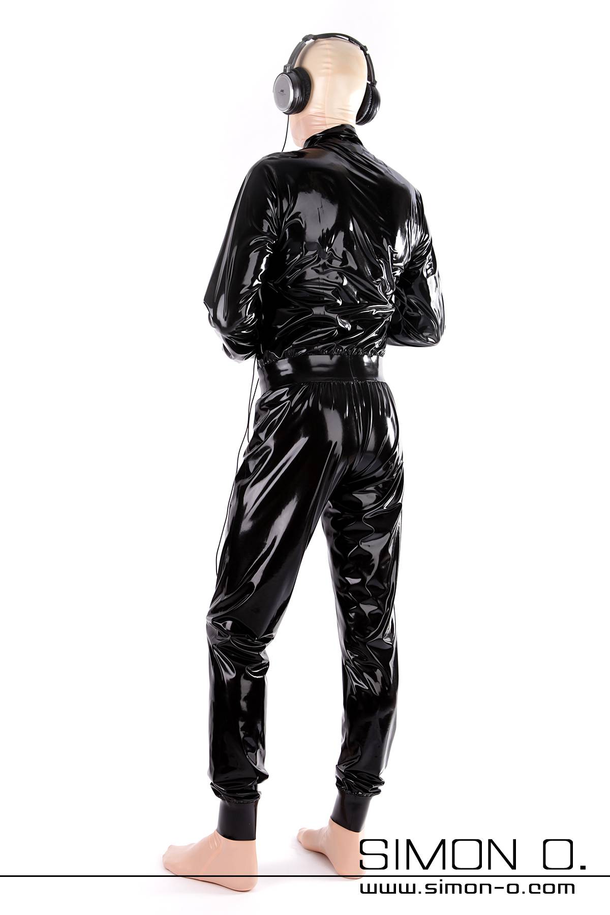 A man wears a loose-fitting latex suit in shiny black latex seen from behind.